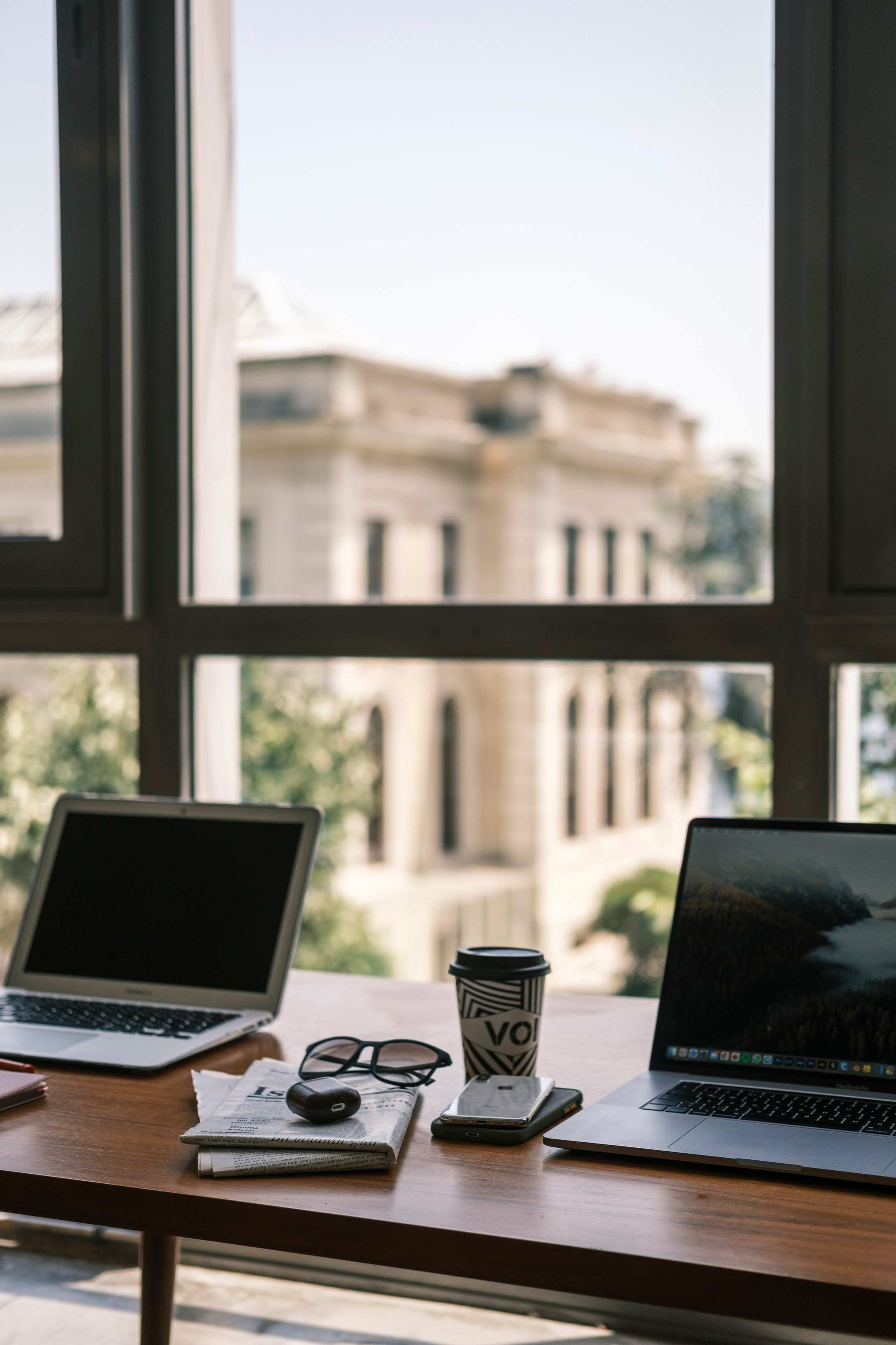 Laptop on a desk near a window in an urban office setting with a city view